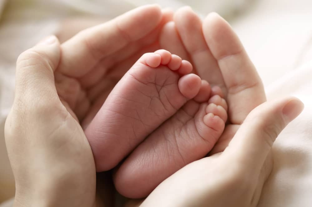 Feet of a baby held by two hands