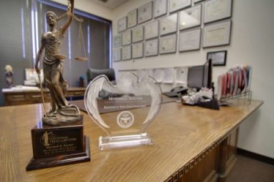 Lady Justice statue and professional awards displayed in a law office