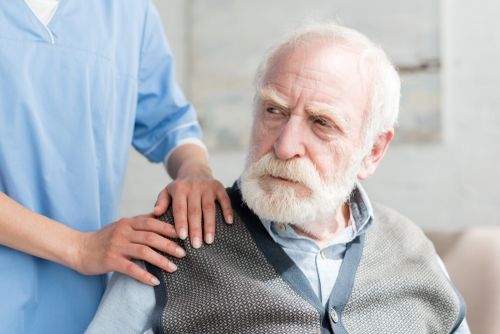 Caregiver with distressed elderly man in nursing home