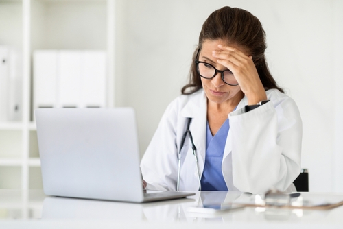 Doctora preocupada revisando expedientes médicos en una computadora