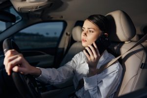 Conductor mirando un teléfono inteligente mientras conduce en el tráfico