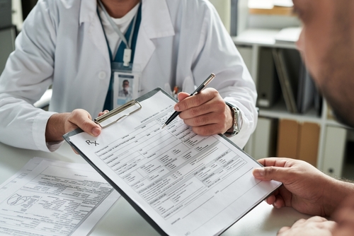 Médico revisando documentos médicos con paciente para página de seguros de negligencia médica