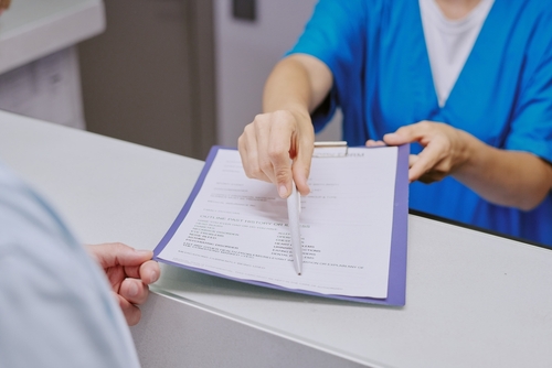 Paciente recibiendo formulario de consentimiento informado en consultorio médico