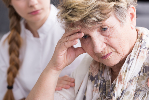 Concerned elderly woman with caregiver in nursing home