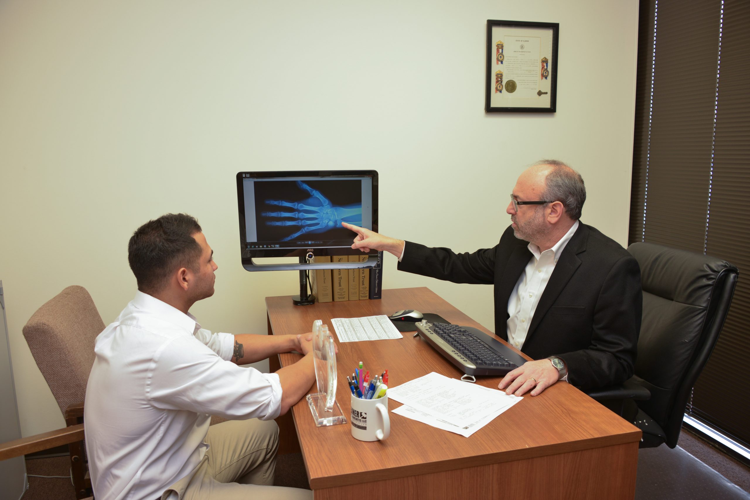Attorney reviewing a hand X-ray with a man in the office