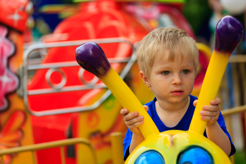 Niño sujetando las barras de seguridad en una atracción de parque de diversiones