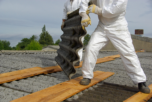 Trabajadores retirando material con asbesto usando trajes de protección