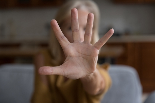 Older woman raising her hand to signal stop, representing nursing home sexual abuse warning signs
