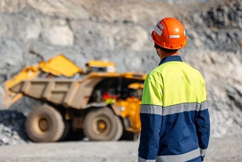Mining worker watching heavy haul truck at quarry site